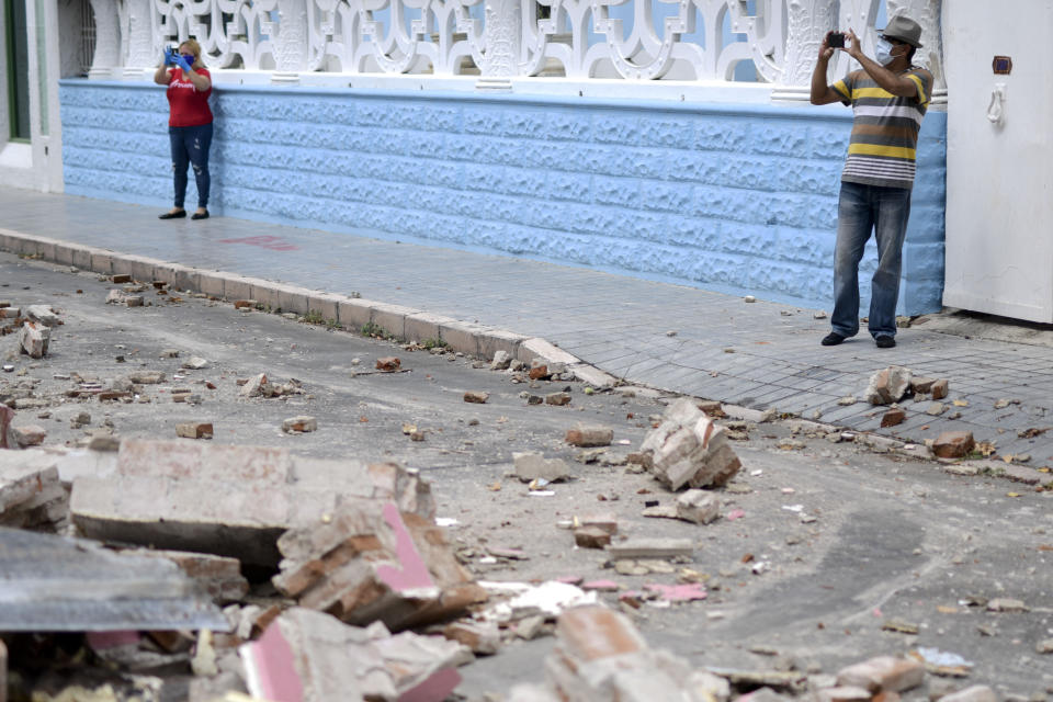 Residents, wearing protective face masks as a precaution against the spread of the new coronavirus, makes photos of damage caused by a 5.4-magnitude earthquake, in Ponce, Puerto Rico, Saturday, May 2, 2020. The quake hit near southern Puerto Rico, jolting many from their beds on an island where some people still remain in shelters from previous quakes earlier this year. (AP Photo/Carlos Giusti)