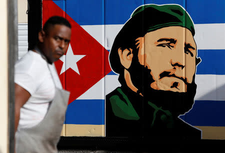 An employee of a state-owned candy store looks outside, near a painting depicting Cuba's former President Fidel Castro, following the announcement of Castro's death, in Havana, Cuba, November 27, 2016. REUTERS/Stringer