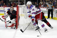 New York Rangers' Kaapo Kakko (24) drives the puck around the net in front of Carolina Hurricanes' Andrei Svechnikov (37) as Hurricanes goaltender Antti Raanta (32) looks on during the first period of Game 2 of an NHL hockey Stanley Cup second-round playoff series in Raleigh, N.C., Friday, May 20, 2022. (AP Photo/Karl B DeBlaker)