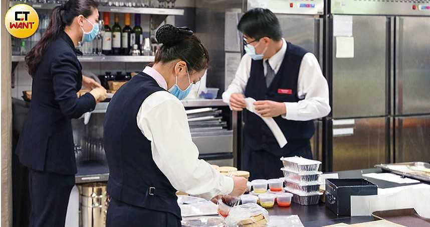 失去餐廳及宴會生意的台北君悅飯店，為搶攻外帶市場推出單價200元的防疫餐盒，接近用餐時間，員工幫忙包裝準備出貨。（圖／王永泰攝）