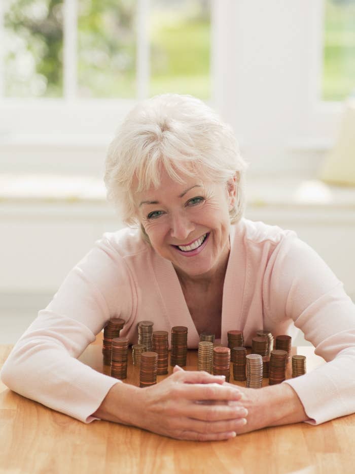 older woman smiling while guarding stacks of coins