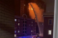 FILE - In this image taken from video, firefighters spray water on a fire at a residential building that killed several people in Urumqi in western China's Xinjiang Uyghur Autonomous Region, on Nov. 24, 2022. What started as an unplanned vigil last weekend in Shanghai by fewer than a dozen people grew hours later into a rowdy crowd of hundreds. The protesters expressed anger over China's harsh COVID-19 policies that they believed played a role in the deadly fire on Nov. 24 in the city in the far west. (AP Photo, File)