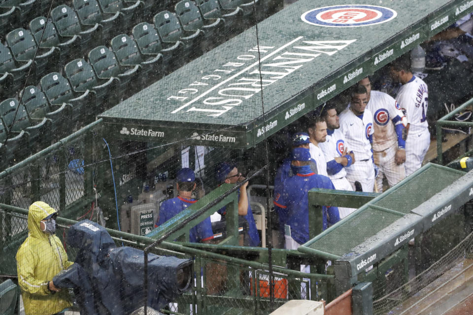 Chicago Cubs players look to the field from the dugout during a rain delay in the ninth inning of a baseball game against the Pittsburgh Pirates in Chicago, Sunday, Aug. 2, 2020. (AP Photo/Nam Y. Huh)