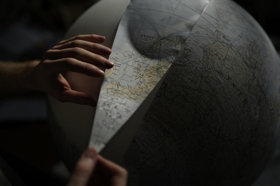 An artist makes a globe at a studio in London, Tuesday, Feb. 27, 2024. Globes in the age of Google Earth capture the imagination and serve as snapshots of how the owners see the world and their place in it. Peter Bellerby made his first globe for his father, after he could not find one accurate or attractive enough. In 2008, he founded Bellerby & Co. Globemakers in London. His team of dozens of artists and cartographers has made thousands of bespoke globes up to 50 inches in diameter. The most ornate can cost six figures. (AP Photo/Kin Cheung)