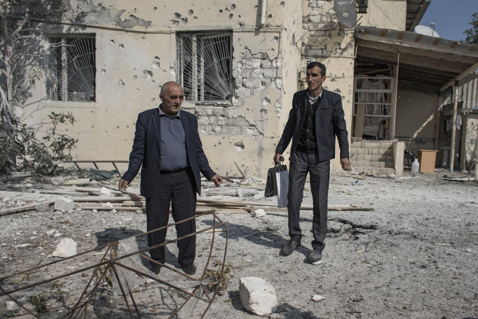 People inspect the damage following overnight shelling by Armenian forces, in the city of Terter, Azerbaijan, Thursday, Oct. 15, 2020. The conflict between Armenia and Azerbaijan continues for a third week despite a Russia-brokered cease-fire deal, as both sides exchanged accusations and claims of new attacks over the separatist territory of Nagorno-Karabakh. (Can Erok/DHA via AP)