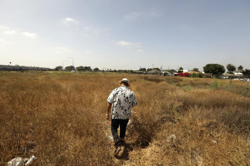 Germán Manrique Magaña, the neighborhood's unofficial neighborhood ombudsman, walks through a 10-acre vacant lot in Watts.