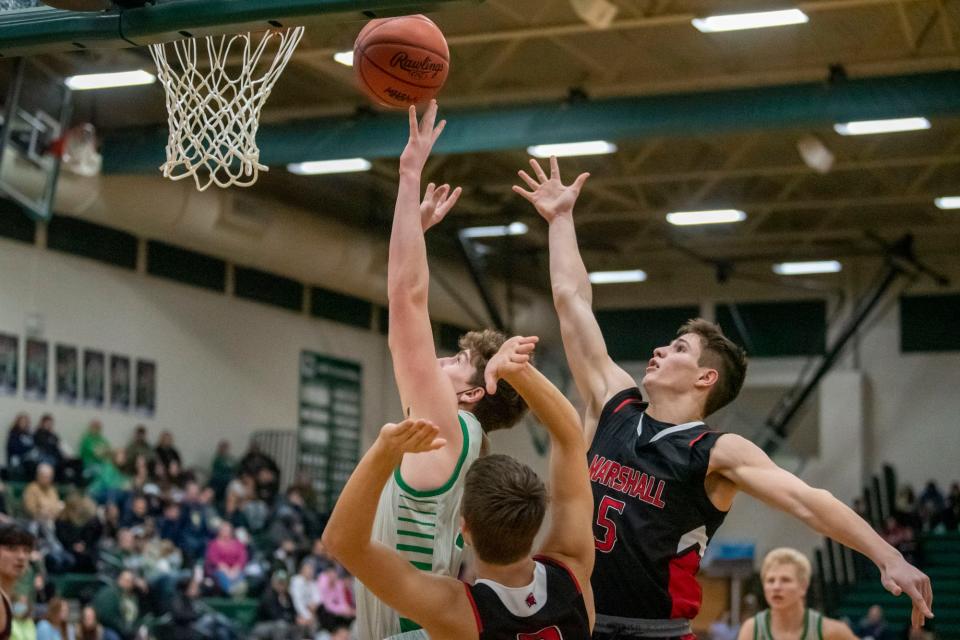 Pennfield junior Brenden Duncan (24) attempts a basket as Marshall senior Nate Tucker (5) and Marshall senior Isaac Stetler (2) guard him at Pennfield High School on Tuesday, Jan. 11, 2022. Pennfield defeated Marshall 48-44.