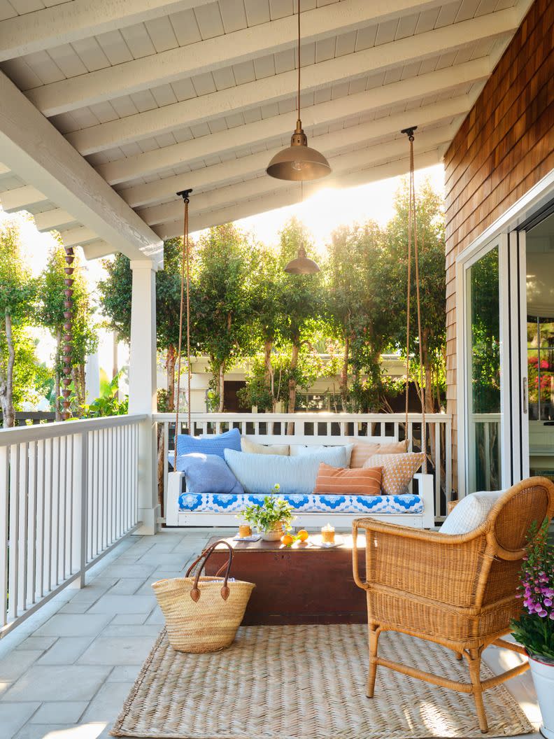 a porch with a swing and wicker chair