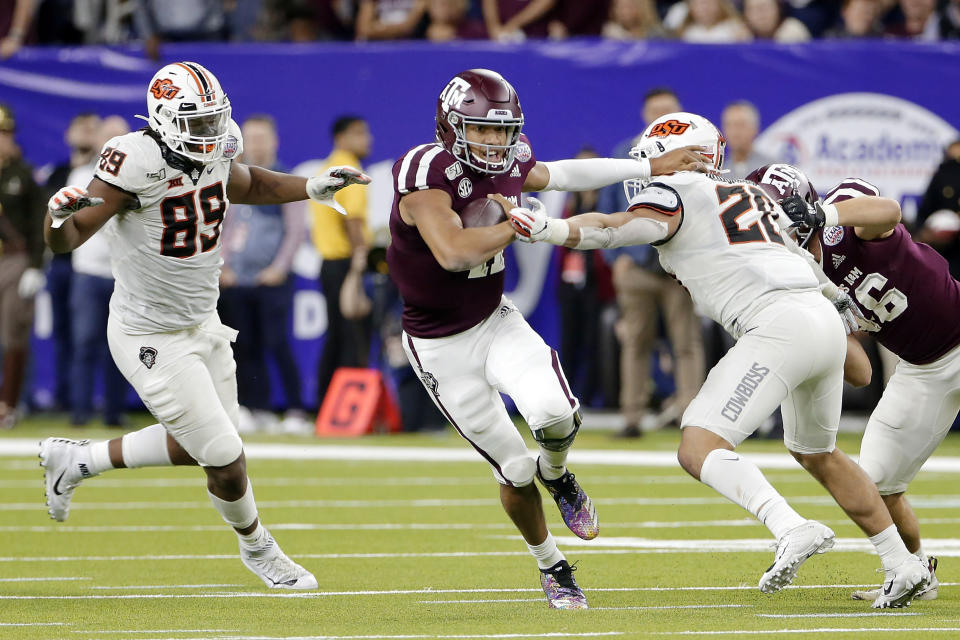 Texas A&M quarterback Kellen Mond (11) gets through the hole between Oklahoma State defensive end Tyler Lacy (89) and safety Malcolm Rodriguez (20) on the way to a touchdown during the second half of the Texas Bowl NCAA college football game Friday, Dec. 27, 2019, in Houston. (AP Photo/Michael Wyke)