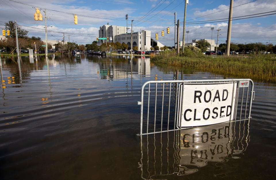 A road closed sign tells motorists to not pass through the floodwaters at a Charleston, S.C., intersection as a king tide rolls in. South Carolina is home to some of the biggest gaps in current flood insurance premiums vs. actual risk.