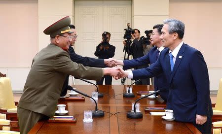 South Korean National Security Adviser Kim Kwan-jin (R), South Korean Unification Minister Hong Yong-pyo (2nd R), Secretary of the Central Committee of the Workers' Party of Korea Kim Yang Gon (2nd L), and the top military aide to the North's leader Kim Jong Un Hwang Pyong-so (L), shake hands during the inter-Korean high-level talks at the truce village of Panmunjom inside the Demilitarized Zone separating the two Koreas, South Korea, in this picture provided by the Unification Ministry and released by Yonhap on August 22, 2015. REUTERS/the Unification Ministry/Yonhap