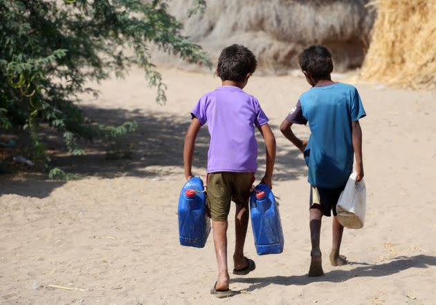 Yemeni children carry jerrycans at a makeshift camp for people who fled fighting between Houthi rebels and the Saudi-backed government forces, in the village of Hays near the conflict zone in Yemen's western province of Hodeida, on Jan. 28. (Photo: KHALED ZIAD via Getty Images)