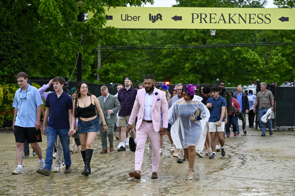 Spectators walk on mud as they head to the grandstand ahead of the Preakness Stakes horse race at Pimlico Race Course, Saturday, May 18, 2024, in Baltimore. (AP Photo/Nick Wass)