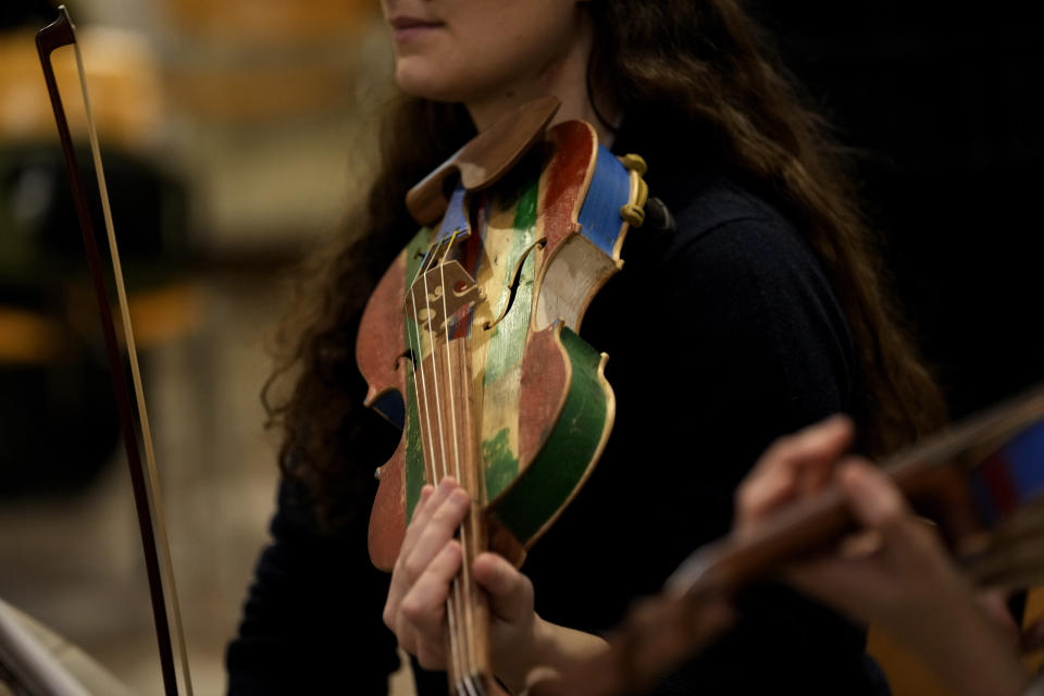 A woman member of the 'Sea Orchestra' rehearses with violin made from the wood of wrecked immigrants' boats in Milan, northern Italy, Saturday, Feb. 10, 2024. Inmates at Milan's maximum security prison Opera took the wood of wrecked boats sailed by migrants across the Sicily Channel to craft the musical instruments that the 'Sea Orchestra' used during their debut at La Scala Opera House in Milan on Monday, Feb. 12, 2024. The violins, violas and cellos played by the Orchestra of the Sea in its debut performance Monday at Milan's famed Teatro all Scala carry with them tales of hardship. (AP Photo/Antonio Calanni)