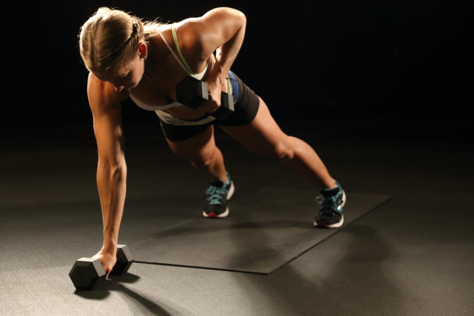 Start in a hollow body, rounded back position. Squeeze your abs and glutes to maintain a good shape while lifting. Lift the dumbbell straight up to your armpit and lower with control. Switch arms and repeat