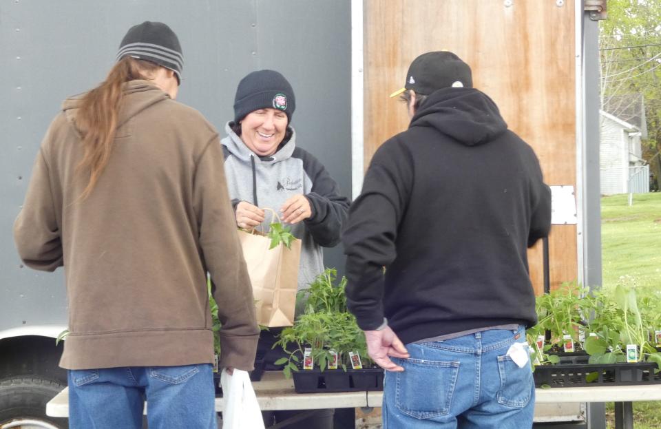 Laurie Risner of Perfection Greenhouse helps customers with a purchase during the Dutchtown Farmers Market in New Washington on Thursday.