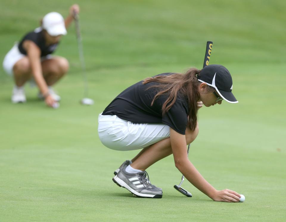 Cara Murphy of Jackson places her ball on the first green during their match against Green at Shady Hollow Country Club on Tuesday, August 31, 2021. In the background Rylee Colangelo of Jackson also places her ball.