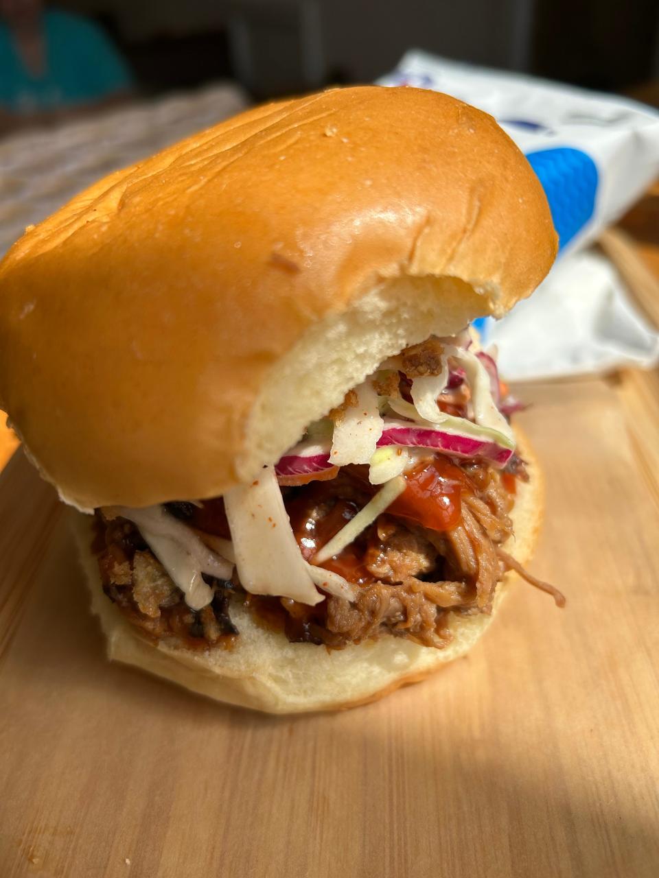 A build-your-own pulled pork sandwich includes a brioche bun, crispy onions and cole slaw at SRINA in Kenmore.