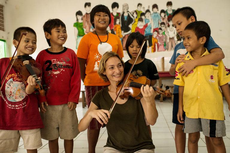 This picture taken on November 29, 2013, shows Italian violinist Sara Michieletto playing violin for street children at a shelter for less fortunate children in Bekasi, on the outskirts of Jakarta