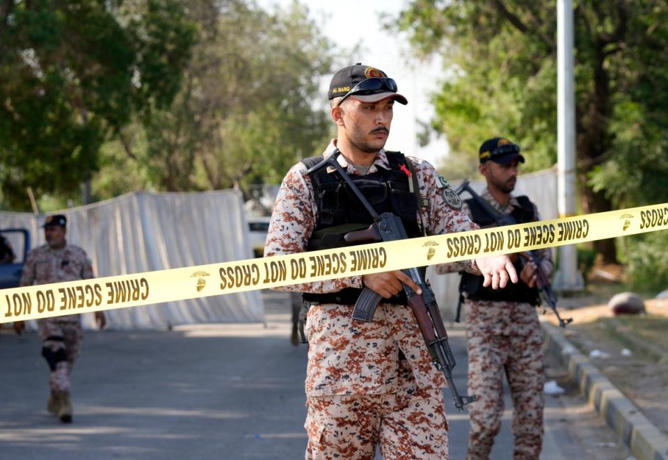 Security officials stand guard at the site of an explosion that caused injuries and destroyed vehicles outside the airport in Karachi, Pakistan, Monday, Oct. 7, 2024. (Copyright 2024 The Associated Press. All rights reserved.)