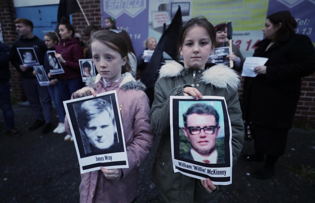 Two children hold pictures of Bloody Sunday victims James Wray and William McKinney during a vigil in West Belfast (PA)