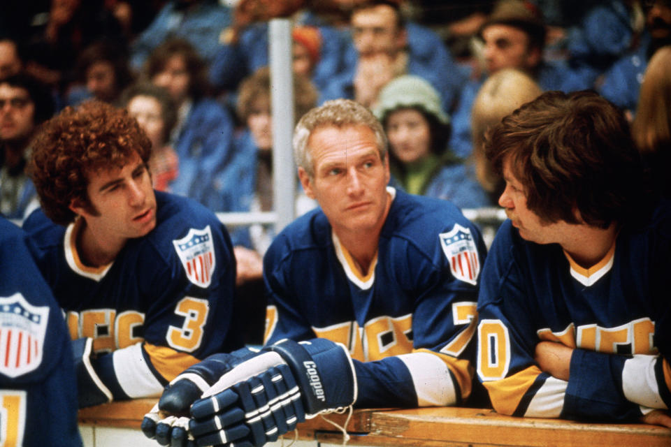 This undated photo provided Courtesy of Universal Pictures shows actors Jerry Houser, left, and Paul Newman, center, in a scene from the movie "Slap Shot." "Slap Shot" was No. 5 in The Associated Press’ Top 25 favorite sports movies poll. (Courtesy of Universal Pictures via AP)