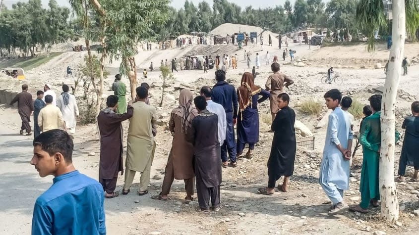 Residents of Jalalabad and Taliban fighters look at the scene of a bombing.