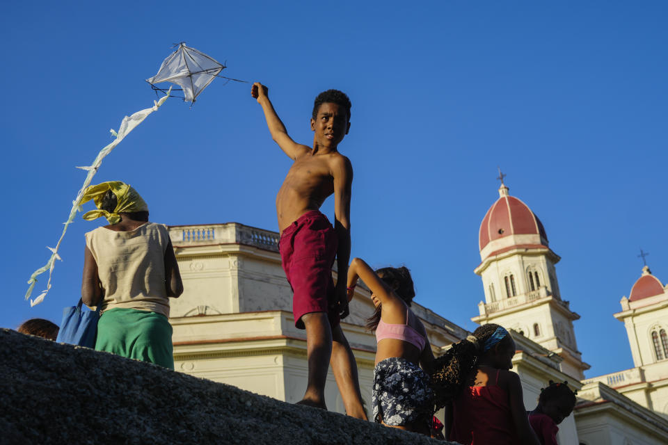 Un niño vuela una cometa fuera del santuario de la Virgen de la Caridad del Cobre en El Cobre, Cuba, el sábado 10 de febrero de 2024. (AP Foto/Ramón Espinosa)