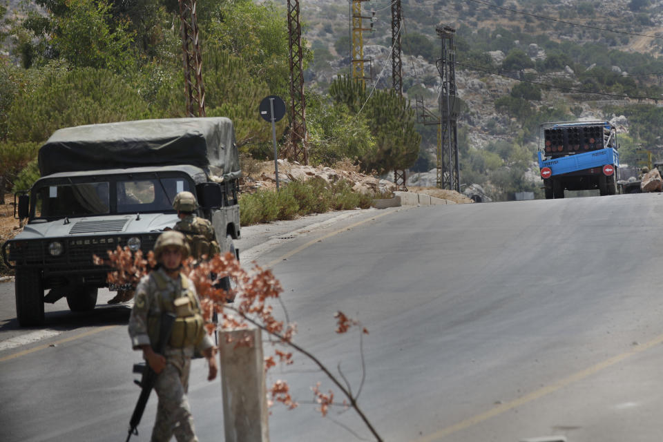 Lebanese army soldiers stand guard in front of a rocket launcher placed on a pick up truck, background, that was used by Hezbollah to fire rockets near Israeli positions, in the southeastern village of Shwaya, near the border with the Golan Heights, Friday, Aug. 6, 2021. The militant Hezbollah group said it fired a barrage of rockets near Israeli positions close to the Lebanese border on Friday, calling it retaliation for Israeli airstrikes on southern Lebanon a day earlier. (AP Photo/Mohammed Zaatari)