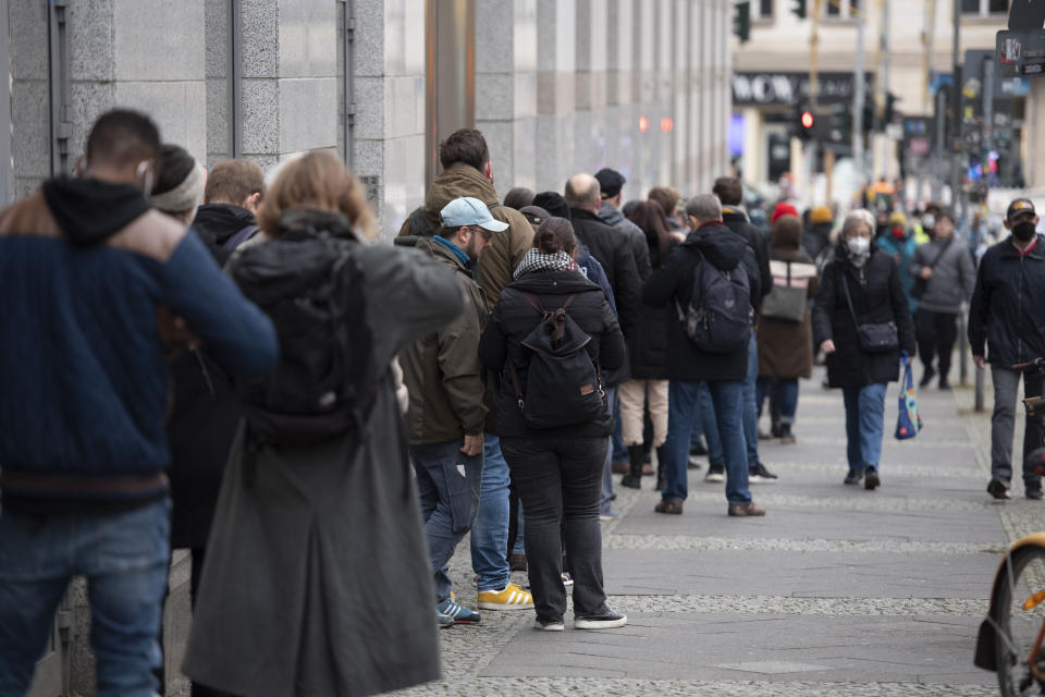 People stand in a queue outside a shopping center and wait to get vaccinated against the coronavirus and the COVID-19 disease in Berlin, Germany, Friday, Nov. 26, 2021. (Paul Zinken/dpa via AP)