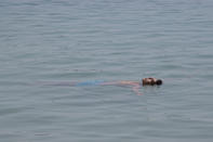 A man floats in the sea during a heatwave, in Alimos suburb, southern Athens, Greece, Monday, Aug. 2, 2021. The heat wave is expected to peak Monday, with temperatures inland ranging from 42 to 46 degrees Celsius (107.6 to 114.8 Fahrenheit). Temperatures will remain at 40 Celsius (104 Fahrenheit) or above in much of Greece until at least Friday, meteorologists say. (AP Photo/Michael Varaklas)