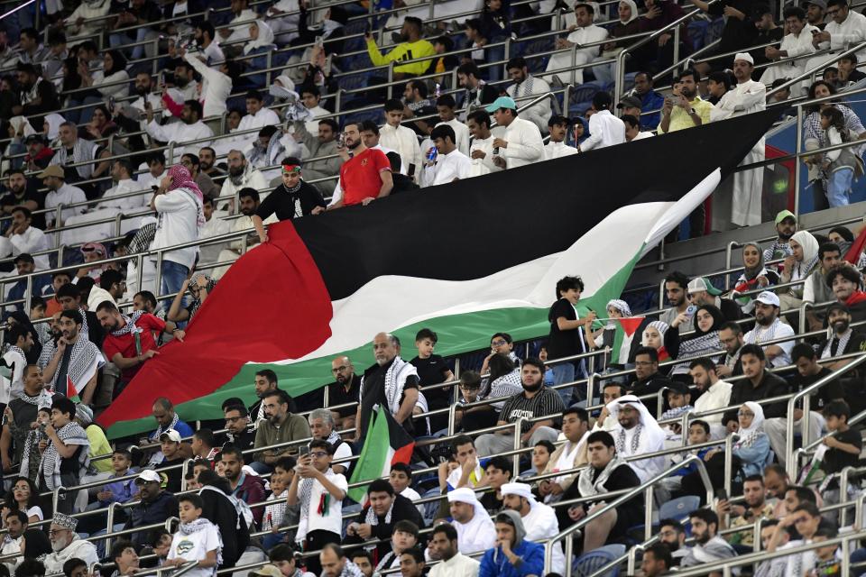 Palestinian fans hold a giant Palestine national flag during a qualifying soccer match against Australia of the FIFA World Cup 2026 at Jaber Al -Ahmad stadium in Kuwait, Tuesday, Nov. 21, 2023. (AP Photo/Jaber Abdulkhaleg)