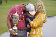 Jon Rahm, of Spain, holds the champions trophy for photographers as he stands with his wife, Kelley Rahm and kisses their child, Kepa Rahm, 11 months, after the final round of the U.S. Open Golf Championship, Sunday, June 20, 2021, at Torrey Pines Golf Course in San Diego. (AP Photo/Marcio Jose Sanchez)