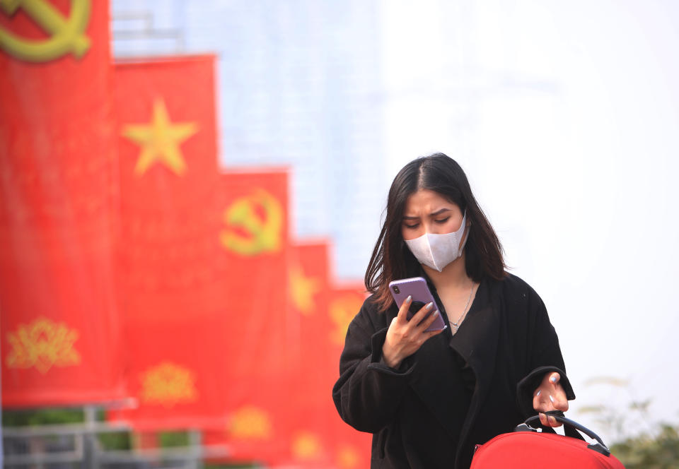 FILE - In this Jan. 23, 2021 file photo, a woman wearing face mask looks at her phone in Hanoi, Vietnam. Vietnam says it has discovered a new coronavirus variant that’s a hybrid of strains first found in India and the U.K. The Vietnamese health minister made the announcement Saturday, May 29. (AP Photo/Hau Dinh, File)