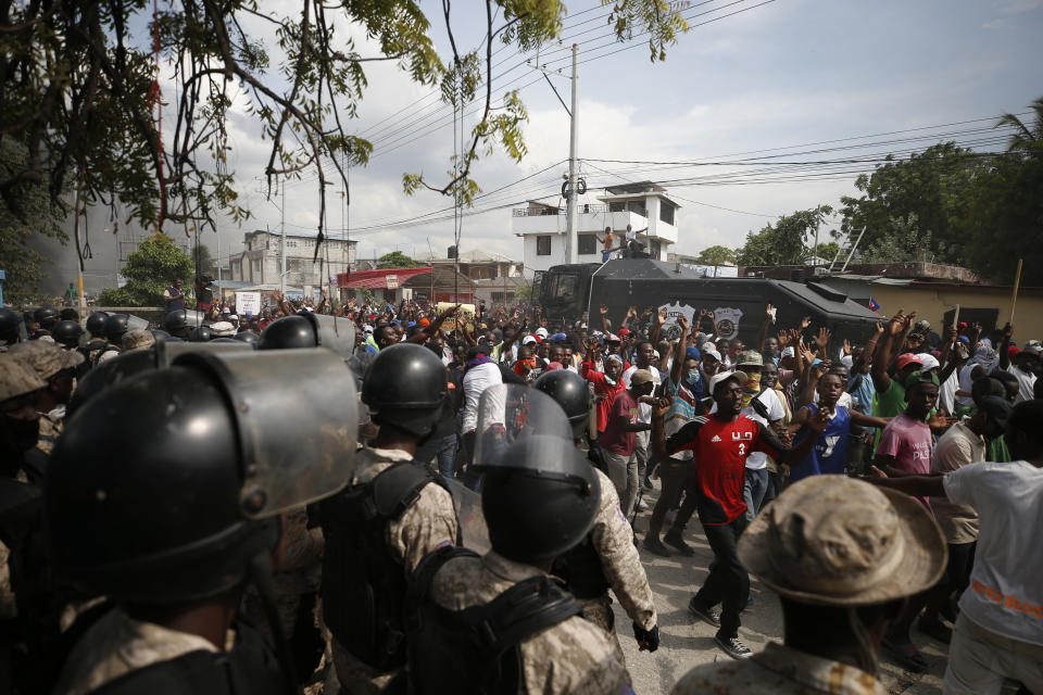 Protesters cheer when police, after firing many rounds of tear gas and other weapons, ultimately stepped aside and let them pass, on their way to United Nations headquarters, in Port-au-Prince, Haiti, Friday, Oct. 4, 2019. Thousands of protesters marched through the Haitian capital to the U.N. headquarters Friday in one of the largest demonstrations in a weekslong push to oust the embattled president Jovenel Moise.(AP Photo/Rebecca Blackwell)