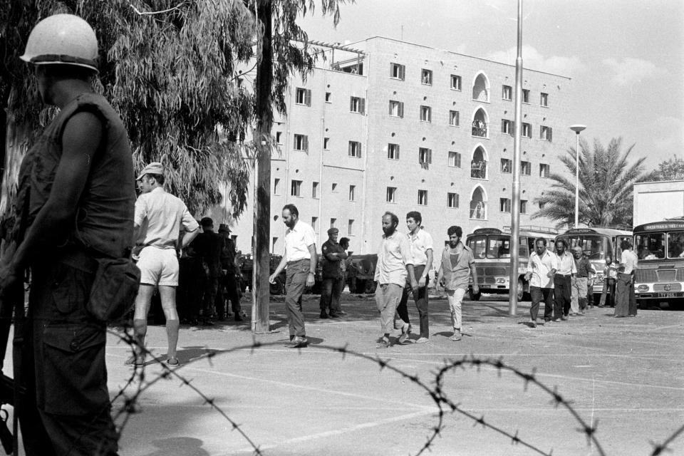 This Sept. 19, 1974, photo provided from the Cyprus' press and informations office shows the Ledra Palace Hotel in the background during the exchange captive soldiers and civilians between Turkish and Cypriots after the 1974 Turkish invasion, in the divided capital Nicosia, Cyprus. This grand hotel still manages to hold onto a flicker of its old majesty despite the mortal shell craters and bullet holes scarring its sandstone facade. Amid war in the summer of 1974 that cleaved Cyprus along ethnic lines, United Nations peacekeepers took over the Ledra Palace Hotel and instantly turned it into an emblem of the east Mediterranean island nation's division. (Press and informations Office, via AP)