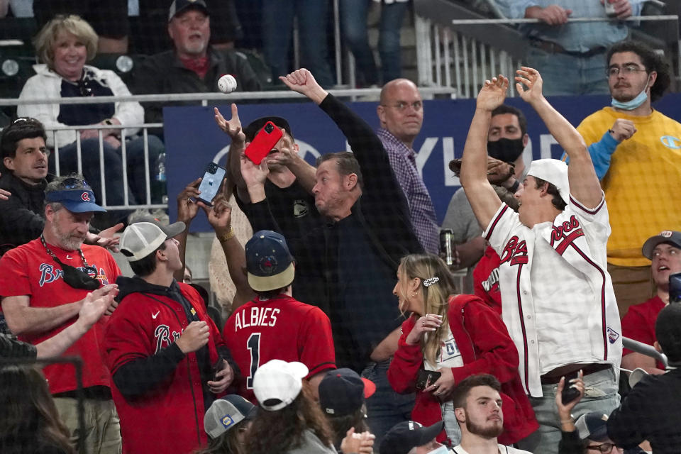 Fans reach for a foul ball during a baseball game between the Philadelphia Phillies and the Atlanta Braves, Friday, May 7, 2021, in Atlanta. Truist Park was open to 100% capacity. (AP Photo/John Bazemore)