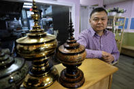 In this Thursday, Feb. 13, 2020, photo, Sai Kyaw, an immigrant from Myanmar, also known as Burma, stands for a photograph near traditional Burmese religious offering vessels at his restaurant in Boston. Kyaw said new travel restrictions are preventing his brother, sister and their families from joining him in Massachusetts after nearly a dozen years in the visa application process. (AP Photo/Steven Senne)