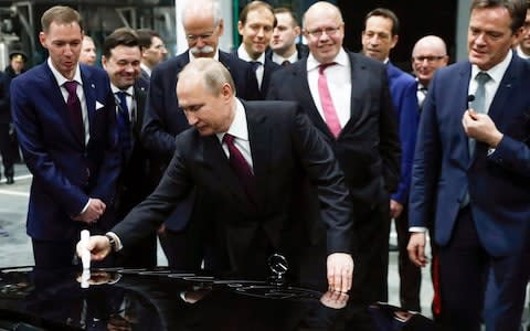 Mr Putin signs a car hood during the opening of a Mercedes Benz plant outside Moscow on Wednesday - Credit: Pavel Golovkin/AFP