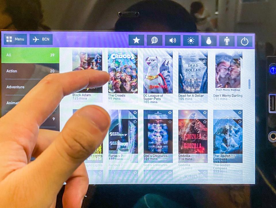 An inflight entertainment screen on the back of a plane seat with entertainment options on each screen