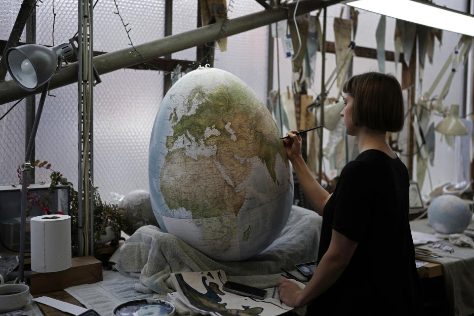 An artist paints a globe at a studio in London, Tuesday, Feb. 27, 2024. Globes in the age of Google Earth capture the imagination and serve as snapshots of how the owners see the world and their place in it. Peter Bellerby made his first globe for his father, after he could not find one accurate or attractive enough. In 2008, he founded Bellerby & Co. Globemakers in London. His team of dozens of artists and cartographers has made thousands of bespoke globes up to 50 inches in diameter. The most ornate can cost six figures. (AP Photo/Kin Cheung)