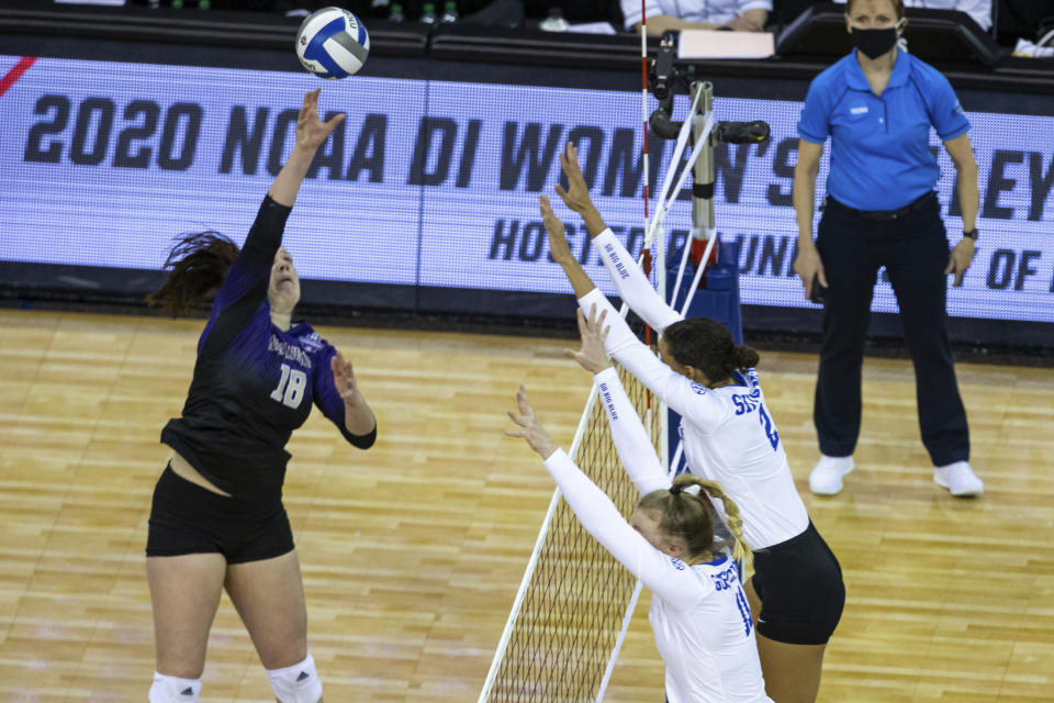 Washington outside hitter Madi Endsley (18) spikes the ball against Kentucky's Elise Goetzinger (11) and Madi Skinner (2) during the first set of a semifinal in the NCAA women's volleyball championships Thursday, April 22, 2021, in Omaha, Neb. (AP Photo/John Peterson)