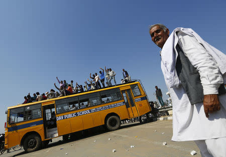 Demonstrators from the Jat community sit on top of a school bus as they block the Delhi-Haryana national highway during a protest at Sampla village in Haryana, India, February 22, 2016. REUTERS/Adnan Abidi