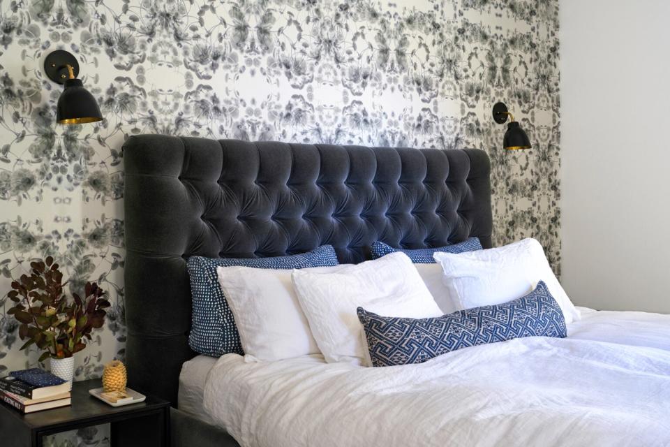 modern primary bedroom with wallpaper and black velvet headboard