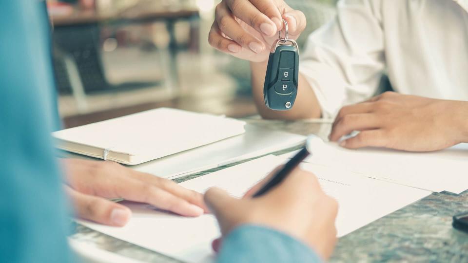 dealer salesman giving car key to new owner.