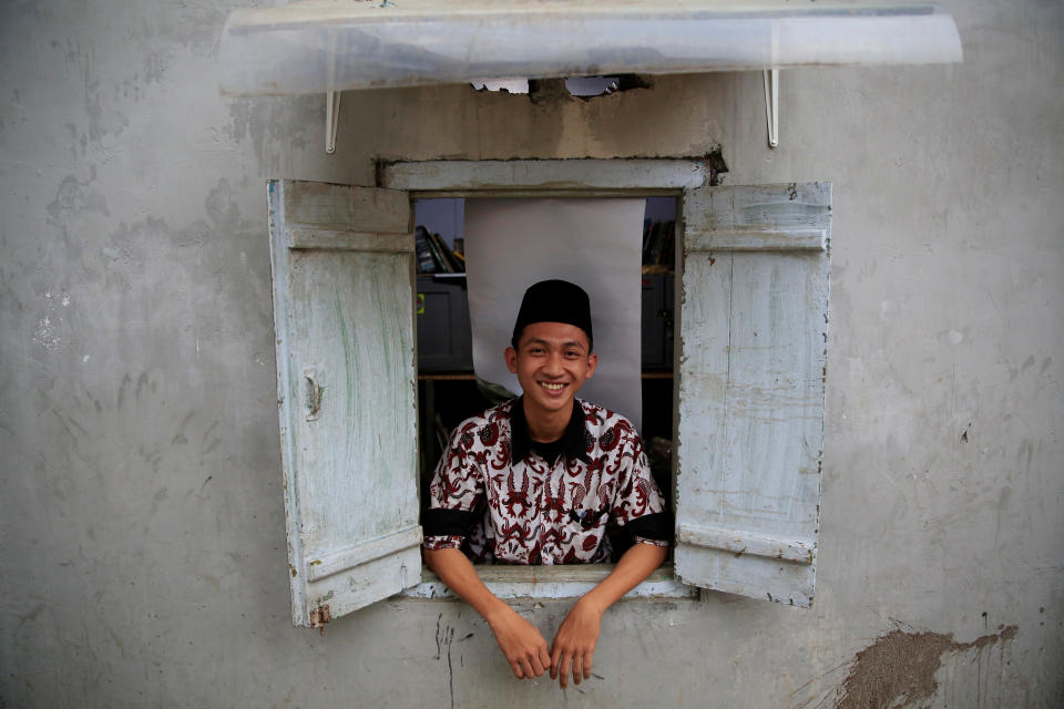 <p>A student poses for a photograph as he looks out from a dormitory window at Lirboyo Islamic boarding school in Kediri, Indonesia, May 19, 2018. (Photo: Beawiharta/Reuters) </p>