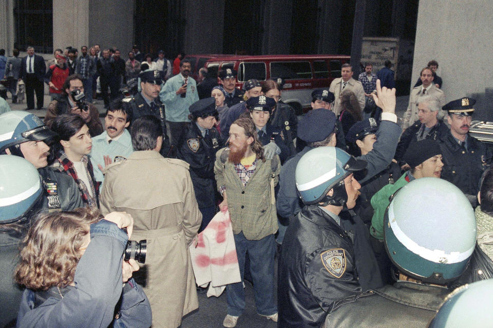 New York City police take into custody some of the demonstrators arrested on Monday, May 1, 1989, on Wall Street as part of a May Day protest in New York. The demonstrators, who called themselves "Resist to Exist," were arrested at Wall Street and Broadway at about 9 a.m., according to the police. (AP Photo/Mario Suriani)