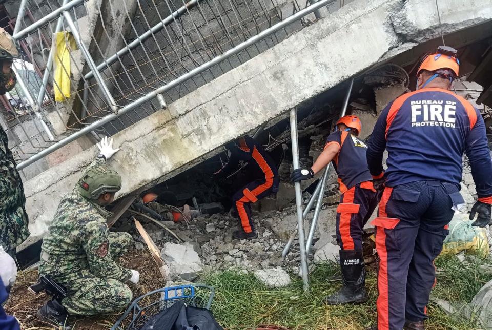 In this handout photo provided by the Bureau of Fire Protection, rescuers try to pull out a trapped resident from under a collapsed structure after a strong earthquake struck La Trinidad, Benguet province, northern Philippines on Wednesday July 27, 2022. A strong earthquake left some people dead and injured dozens in the northern Philippines on Wednesday, where the temblor set off small landslides and damaged buildings and churches and prompted terrified crowds and hospital patients in the capital to rush outdoors.