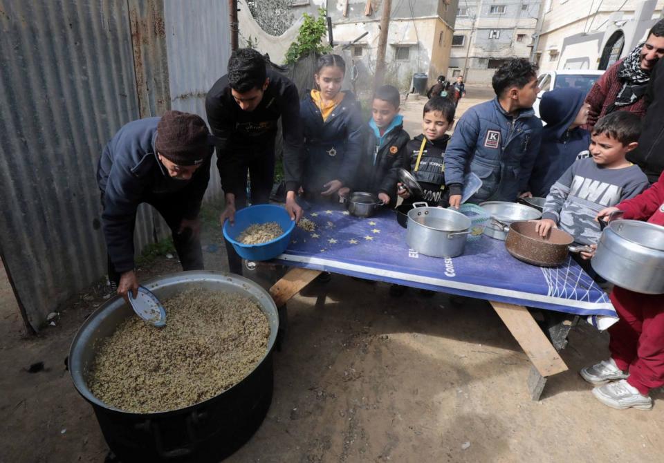 PHOTO: Palestinian people holding empty bowls try to reach out for food distributed by volunteers at donation point as Israeli attacks continue in Dair El-Balah, Gaza on January 26, 2024.  (APA/Shutterstock)