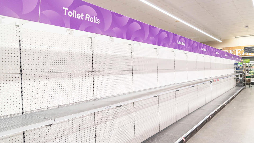 An empty row of toilet paper rolls in a supermarket.